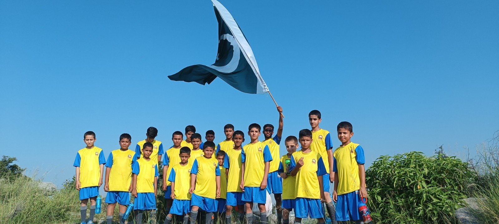 Students raising the flag of Pakistan together.